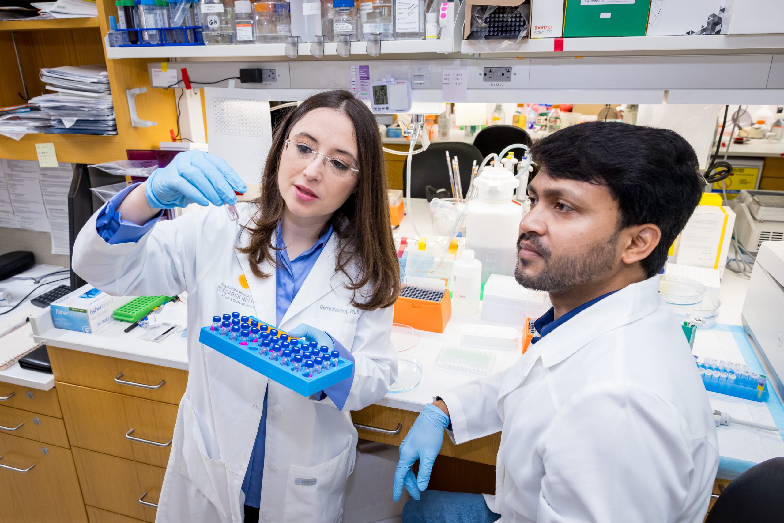 Two scientists working together in a lab examining sample tubes.